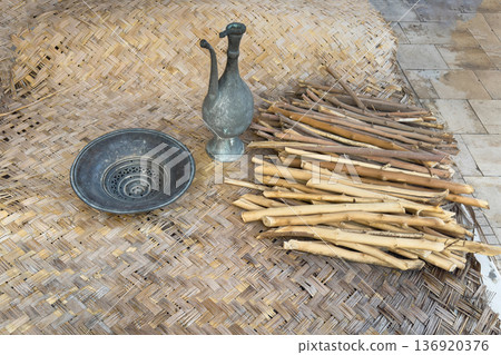 An antique oriental jug and a bowl sit on a woven rug 136920376