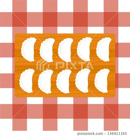 Dumplings on a wooden cutting board on red checkered tablecloth 136921165