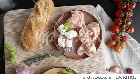 High-quality farm food on wooden cutting board. Top view. Flat lay photo. Soft goat cheese on bread, basil and mortadella sandwich. Italian tradition cuisine. High-quality farm food on wooden cutting board. Top view. Flat lay photo. Soft goat cheese on bread, basil and mortadella sandwich. Italian tradition cuisine. 136921822