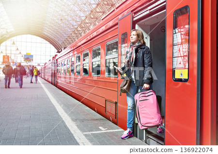 Woman tourist with suitcase coming out of train Woman tourist with suitcase coming out of train 136922074
