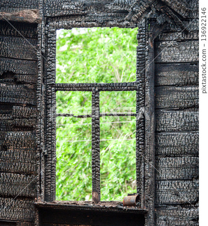 Charred wooden window frame of a burned down house. Burnt broken wood wall 136922146