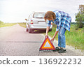 Woman installing emergency sign on road near car 136922232