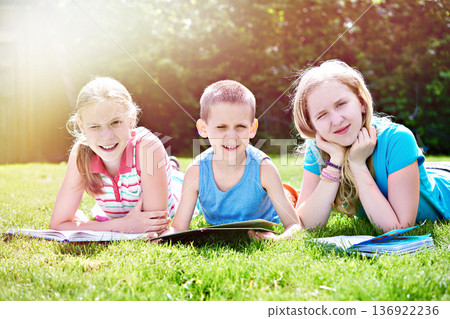 Children reading book on grass 136922236