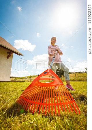 Unusual angle of woman raking leaves 136922263