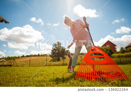 Unusual angle of woman raking leaves Unusual angle of woman raking leaves 136922264