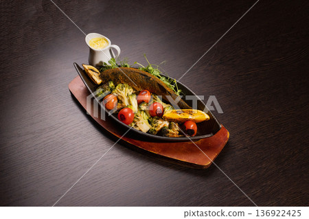 Baked fish with vegetables and sauce in a plate on 136922425