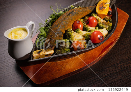 Baked fish with vegetables and sauce in a plate on Baked fish with vegetables and sauce in a plate on 136922449