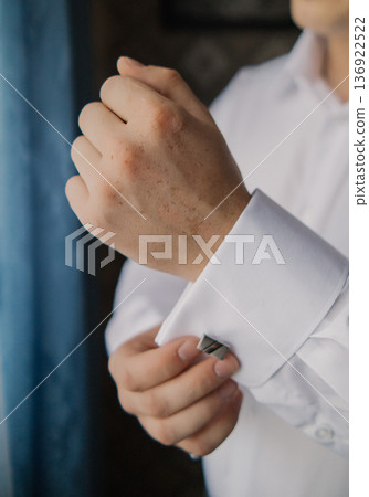 A man adjusts his shirt sleeve A man adjusts his shirt sleeve 136922522
