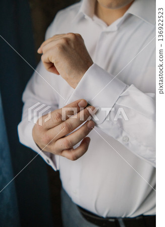 A man adjusts his shirt sleeve A man adjusts his shirt sleeve 136922523