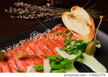 A plate with sliced red fish, bread and greens A plate with sliced red fish, bread and greens 136922770
