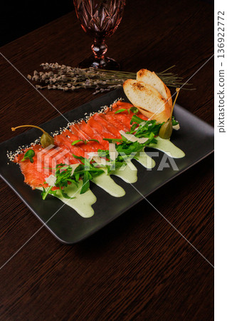 A plate with sliced red fish, bread and greens A plate with sliced red fish, bread and greens 136922772