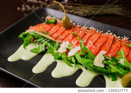 A plate with sliced red fish, bread and greens 136922775