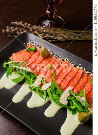 A plate with sliced red fish, bread and greens 136922776