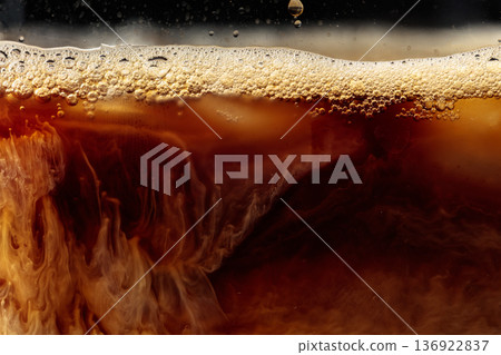 Cream is poured into a glass with iced coffee. Cream is poured into a glass with iced coffee. 136922837