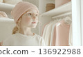 Little blond child girl with glasses and a hat in beige dressing room 136922988