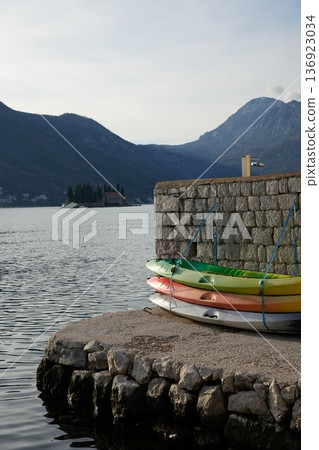 Colorful Kayaks Stacked on Dock with Mountains 136923034