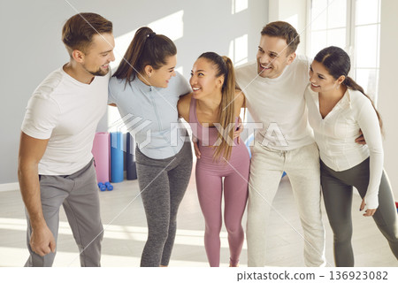 Portrait of happy joyful sporty people group standing in a row in gym after successful fit training Portrait of happy joyful sporty people group standing in a row in gym after successful fit training 136923082