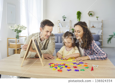 Parents helping daughter learn numbers and alphabet using chalkboard at home Parents helping daughter learn numbers and alphabet using chalkboard at home 136924354