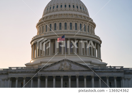 Last beams of golden sunlight on the United States Capitol Building in Washington, DC, with the American flag waving. Dramatic view 136924362