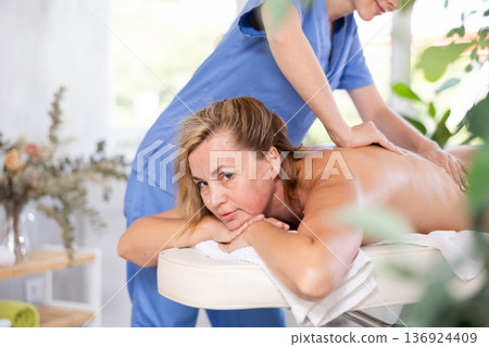 Woman enjoying relaxing massage from professional female masseur 136924409