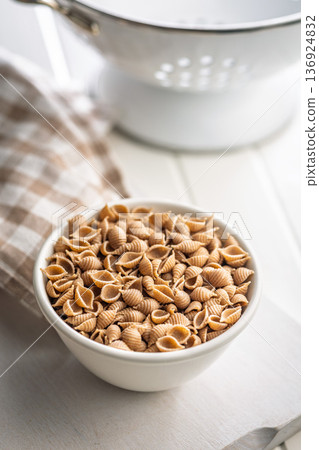 Wholegrain conchiglie pasta in bowl on white table. 136924832