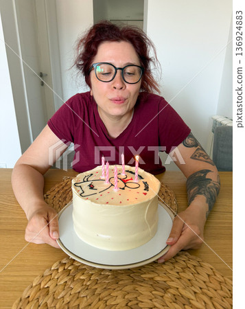 Woman blowing out candles on birthday cake. Celebration, tradition and joyful wish-making moment at festive party. 136924883