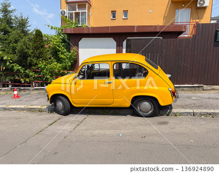 Vintage yellow car parked on the street. Classic automobile, retro transportation, and nostalgia. Vintage yellow car parked on the street. Classic automobile, retro transportation, and nostalgia. 136924890