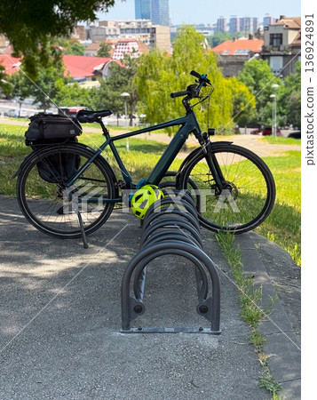 Bicycle parked outdoors with helmet on a stand. Urban mobility, active lifestyle and eco-friendly transport. 136924891