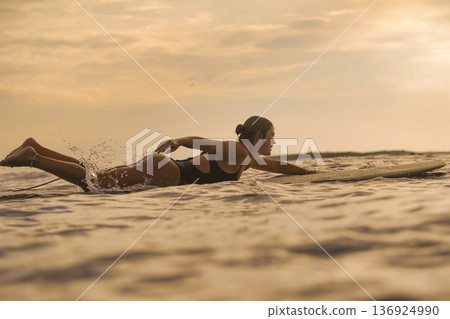 Vibrant Young Lady Participates In Surfing As Sunset Colors Sky Vibrant Young Lady Participates In Surfing As Sunset Colors Sky 136924990