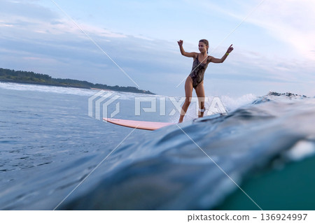 Peaceful Woman Cruises Smoothly Along Shoreline On Her Longboard Peaceful Woman Cruises Smoothly Along Shoreline On Her Longboard 136924997