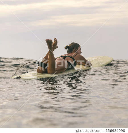 Female Comfortably Lying On Board Amidst Evening Waves And Sky Female Comfortably Lying On Board Amidst Evening Waves And Sky 136924998