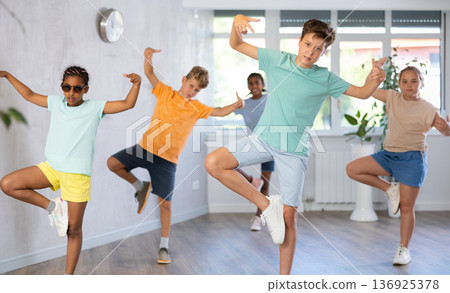 Girls and boys doing dance workout during group class in fitness center Girls and boys doing dance workout during group class in fitness center 136925378