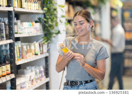 Girl choosing organic cosmetics in eco-friendly produce store Girl choosing organic cosmetics in eco-friendly produce store 136925381