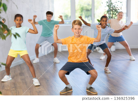 Tweenager dancing krump with group of children in dance studio 136925396
