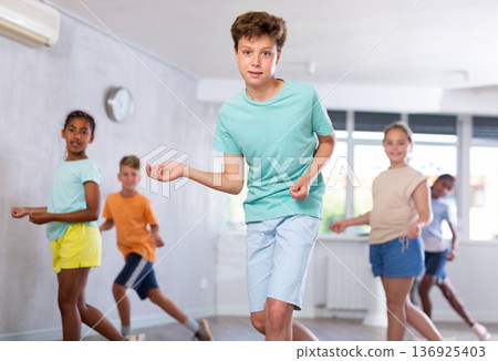Dancing group of five children practicing new dance in modern studio 136925403
