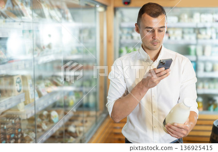 Man in supermarket scan QR code on bottle of milk Man in supermarket scan QR code on bottle of milk 136925415