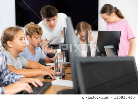 Preteen girl working with computer programs in training room Preteen girl working with computer programs in training room 136925430