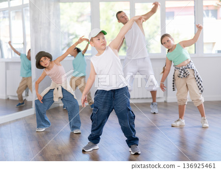 Girls and boys training hip hop in dance studio, dance classes for kids Girls and boys training hip hop in dance studio, dance classes for kids 136925461