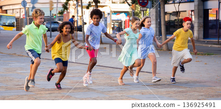 Happy tween friends running together on summer city street 136925491