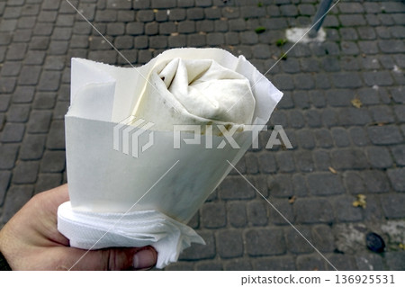 Enjoying a Doner Kebab While Walking on a City Street in the Afternoon 136925531