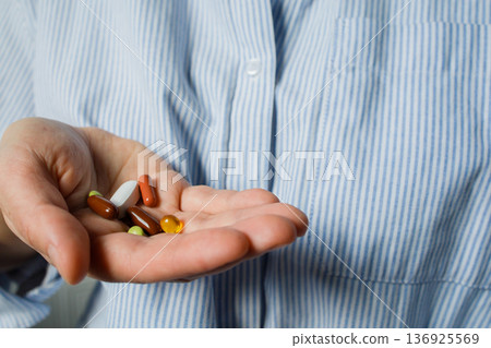 A handful of different pills in woman hand close up. Daily dose of medicines, vitamins, dietary supplements. Health care and control, medical treatment A handful of different pills in woman hand close up. Daily dose of medicines, vitamins, dietary supplements. Health care and control, medical treatment 136925569