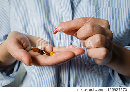 A handful of different pills in woman hands close up. Daily dose of medicines, vitamins, dietary supplements. Health care and control, medical treatment. 136925570