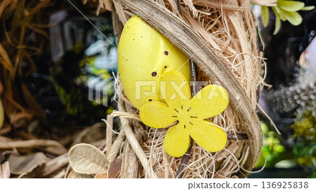 Rustic Easter decoration with yellow wooden flowers, speckled eggs and straw, festive spring background. 136925838