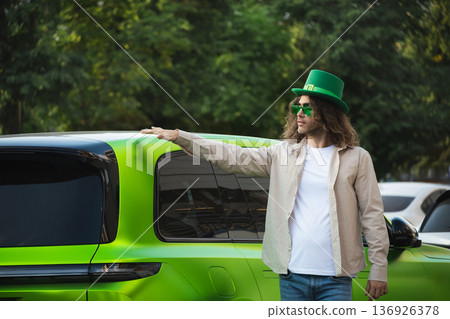 Man standing near green car celebrating holiday Man standing near green car celebrating holiday 136926378