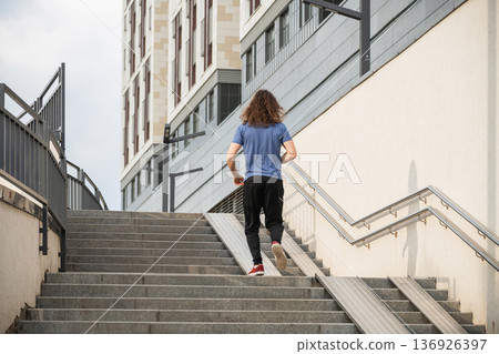 Man walking up stairs in urban environment from behind Man walking up stairs in urban environment from behind 136926397
