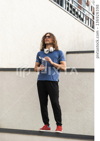 Confident sporty man standing on ledge in urban setting Confident sporty man standing on ledge in urban setting 136926398