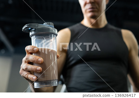 Man holding protein shake in gym after workout, close up fitness lifestyle Man holding protein shake in gym after workout, close up fitness lifestyle 136926417