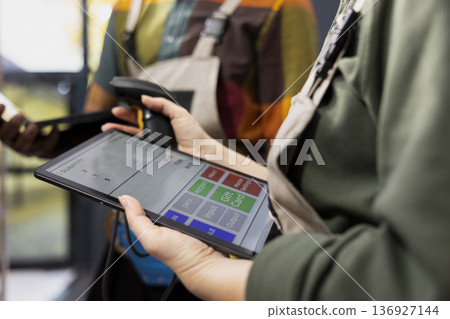 Close up of workers checking inventory with tablet and scanner, verifying airway bills on parcels and supporting e-business operations with shipment labels. Distribution logistics for orders. Close up of workers checking inventory with tablet and scanner, verifying airway bills on parcels and supporting e-business operations with shipment labels. Distribution logistics for orders. 136927144