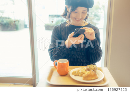 Japanese woman taking a photo of bread at a cafe Japanese woman taking a photo of bread at a cafe 136927323