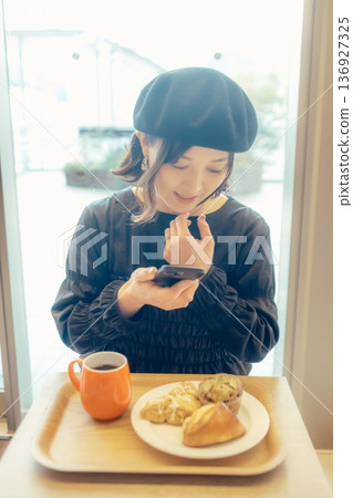 一位日本女子在咖啡館為麵包拍照 一位日本女子在咖啡館為麵包拍照 136927325